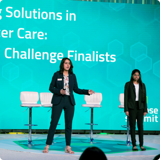 young female entrepreneurs presenting on stage with a large aqua led screen in background at synapse summit in tampa